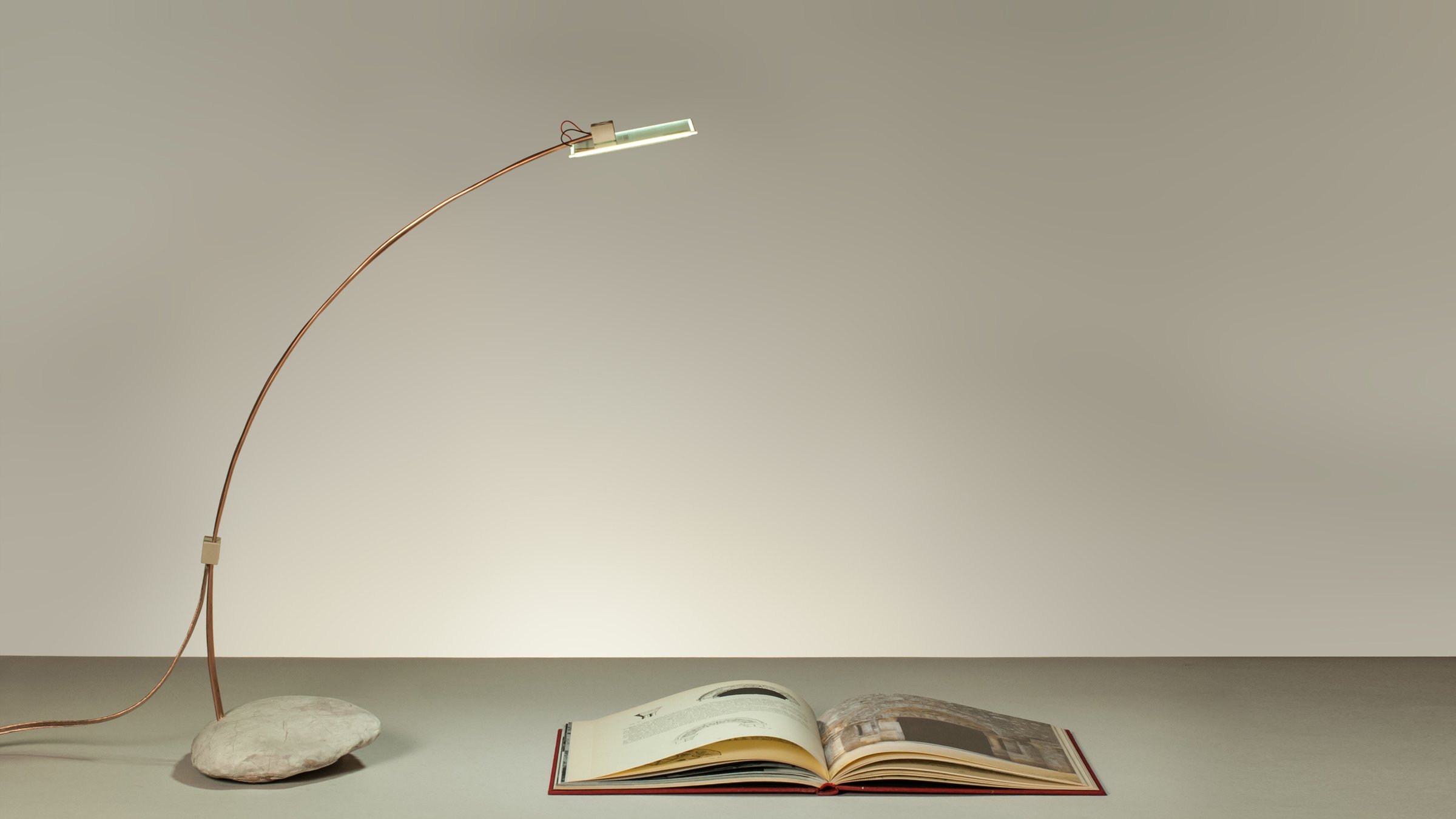 Cruda, lampada da tavolo a OLED in contrasto con una pietra